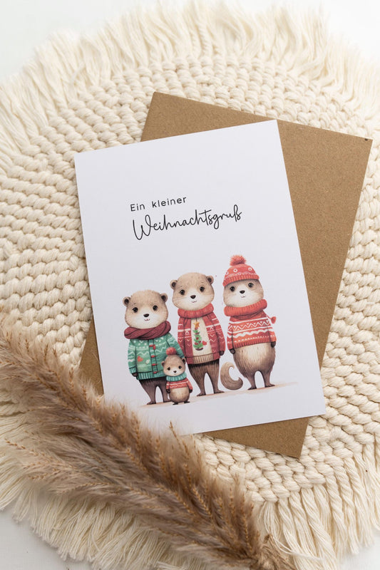 Weihnachtskarte im Format A6 mit einer süßen Otter-Familie mit Weihnachtspullovern im Aquarell-Look und dem Text "Ein kleiner Weihnachtsgruß".